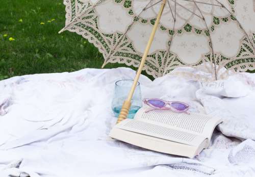 Novel Lays Open Under A Cloth Parasol On A Picnic Blanket Photo