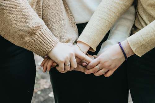 The Arms Of People In Sweaters Holding Hands Photo