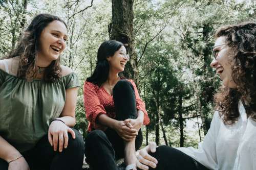 Three People Laughing Under A Tree In A Forest Photo