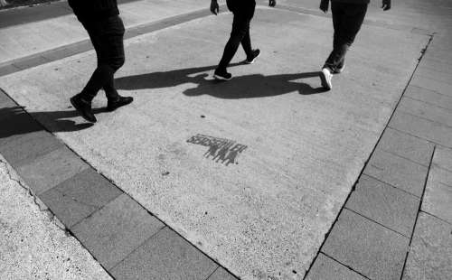 Legs Of Three People Walking In Black And White Photo