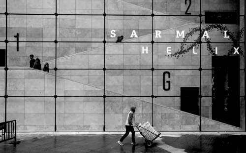 Person Walking By Large Grid Window In Black And White Photo
