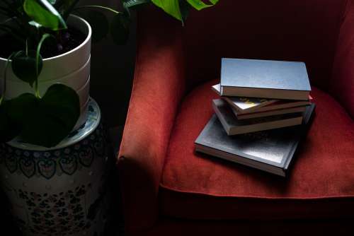 Looking Down At A Stack Of Books On A Red Sofa Chair Photo