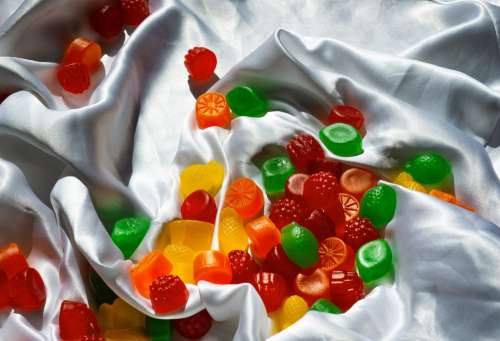 Candy Scattered On White Silk Fabric Photo