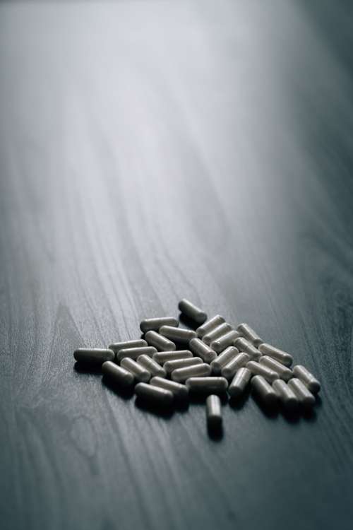 White Pills On A Grey Wood Grain Surface Photo