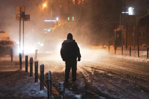 Person Illuminated By Street Lights During A Snow Storm Photo