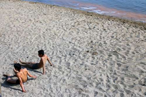 Two People Relax Laying Down On A Sandy Beach Photo