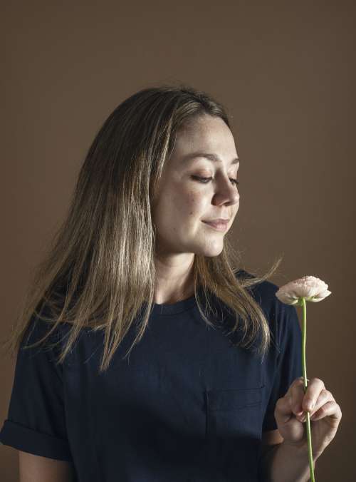 Woman In Blue With Long Brown Hair Holds A Flower Photo
