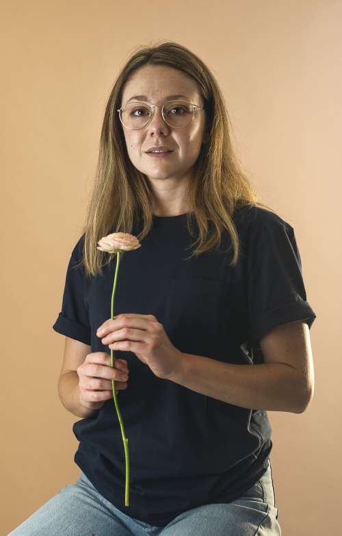 Woman In Blue Holds A Flower And Looks At The Camera Photo