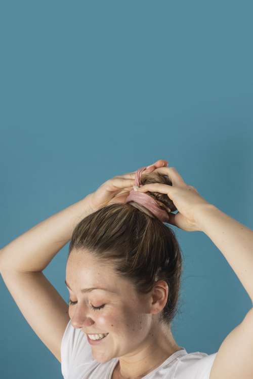 Woman Smiles As She Puts Her Hair Up In A Sparkly Scrunchie Photo