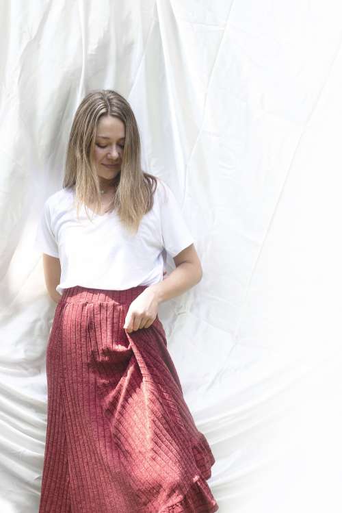 Woman In White Shirt And Red Skirt Against Cloth Backdrop Photo