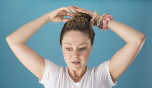 Woman Puts Her Hair In A High Bun With A Scrunchie Photo