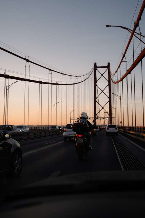 Cars And A Motorbike Driving Along Bridge At Sunset Photo