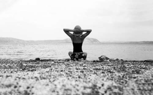Person On A Beach With Their Hands Up In Black And White Photo