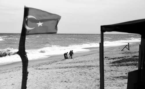 A Flag And People On A Beach In Black And White Photo