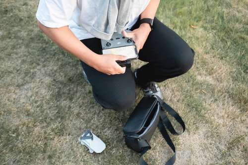 Person Crouches As They Put The Controls Of A Drone Together Photo