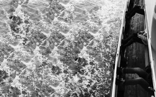 Black And White Photo Of Waves And People In A Boat Photo