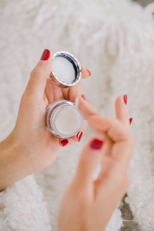 Hands With Red Nails Hold A Small Cosmetics Container Photo