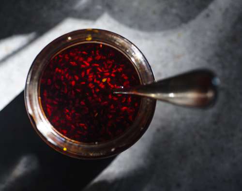Camera Looks Down At A Glass Jar Filled With Red Sauce Photo
