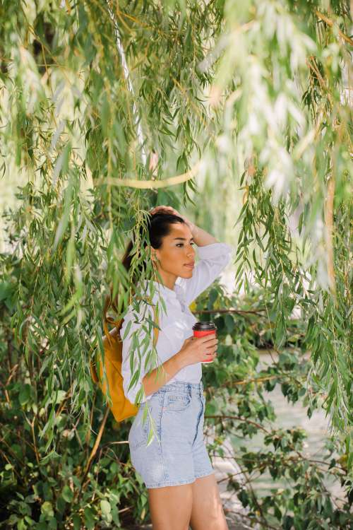 Person Stands Surrounded By Willow Tree Leaves Photo