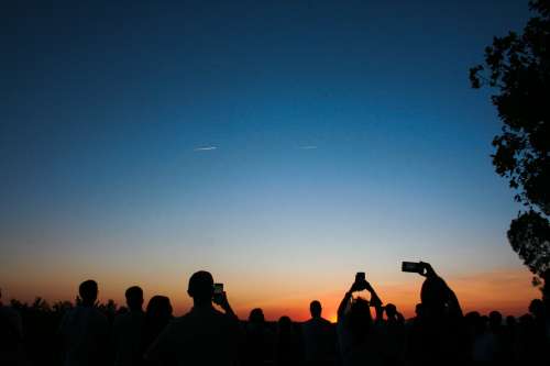 Silhouetted People Taking Pictures Of The Sky Photo