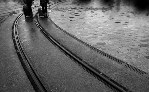 Black And White Photo Of Train Lines And Two Peoples Legs Photo