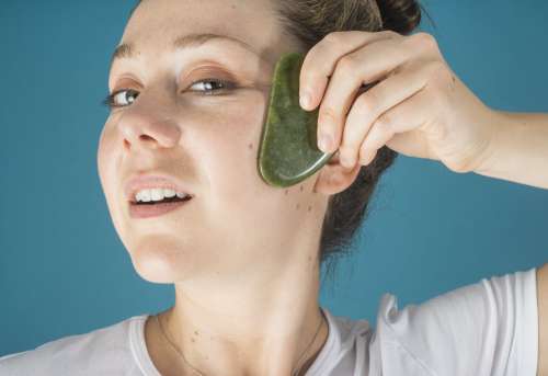Woman Holds A Jade Face Massager To Her Face Photo