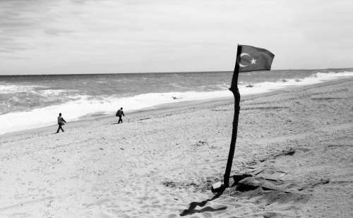Flag On A Wooden Stick In The Sand Photo