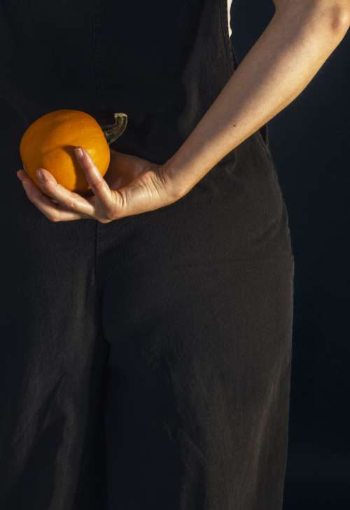 Person Holds A Pumpkin Behind Their Back Photo