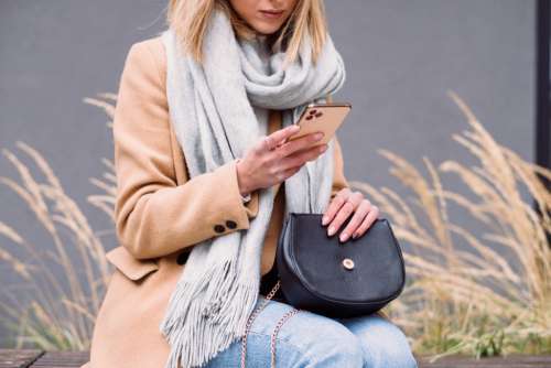 Female holding her phone and purse on an autumn day