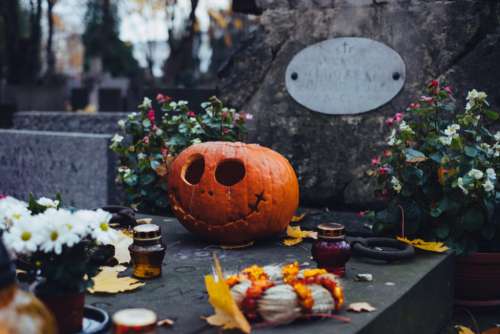 A carved pumpkin on an old grave at the cemetery