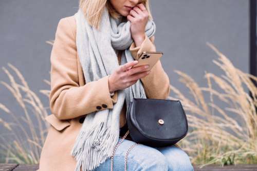 A female holding her phone looking worried on an autumn day 2