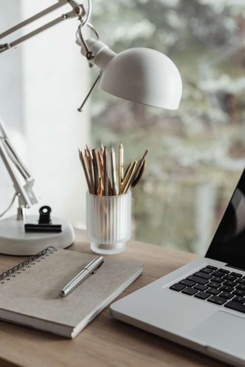 Home office desk with laptop by a large window