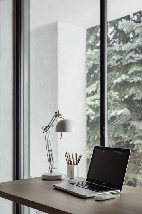 Home office desk with laptop by a large window