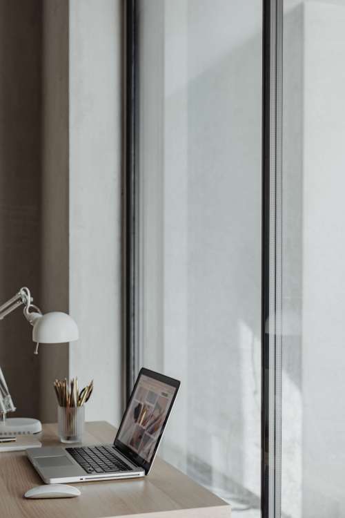 Home office desk with laptop by a large window