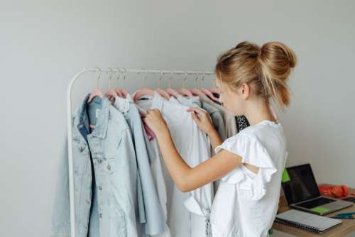 A teenager picks clothes from a hanger in her room