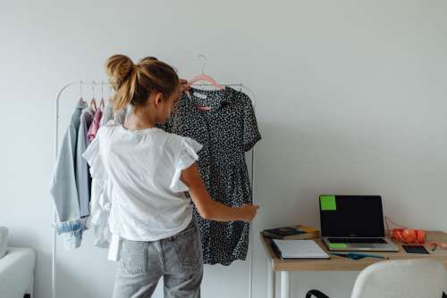 A teenager picks clothes from a hanger in her room
