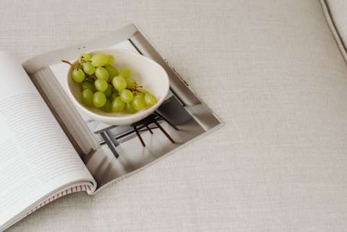 Magazine and grapes in a bowl on a linen couch