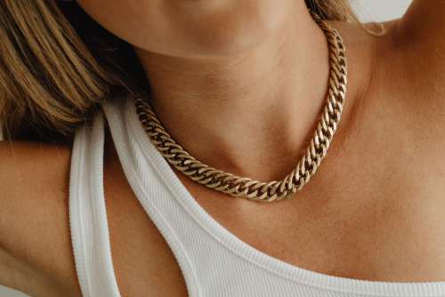 Beautiful woman with gold jewelry - unrecognizable female wearing chain necklace and earrings