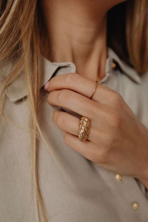 Details of gold jewelry - beautiful woman wearing a tan silk shirt