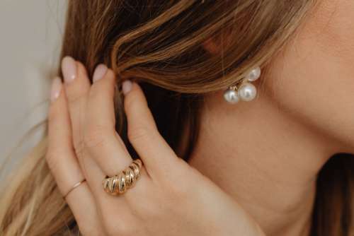 Details of gold jewelry - beautiful woman wearing a tan silk shirt