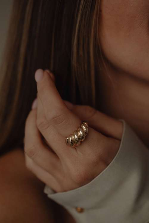 Details of gold jewelry - beautiful woman wearing a tan silk shirt