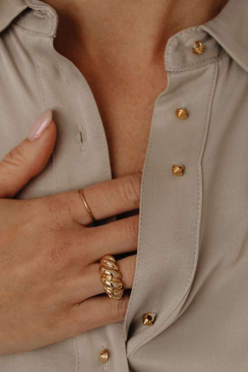 Details of gold jewelry - beautiful woman wearing a tan silk shirt