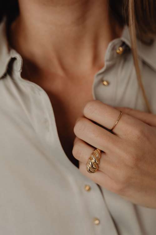 Details of gold jewelry - beautiful woman wearing a tan silk shirt