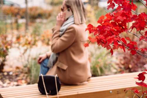 Female sitting on a bench and talking on the phone blur