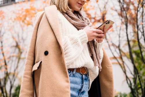 Smiling female holding her phone on an autumn day closeup 3