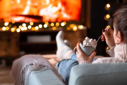 Female relaxing on a sofa holding a mug on Christmas 3
