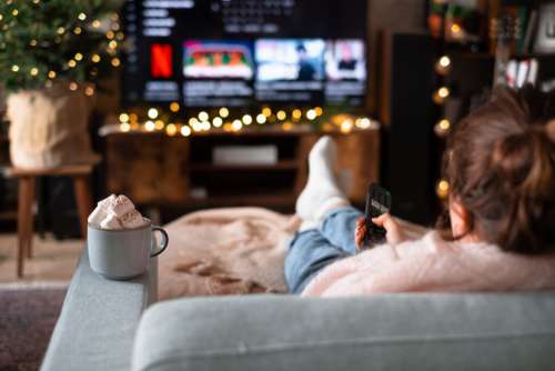 Female sitting on a sofa holding a remote control on Christmas