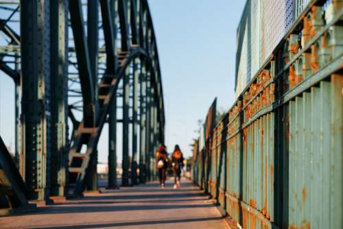 Two females walking across a rusty industrial overpass 3