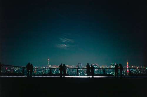 Silhouetted Couples Look Out At A City At Night Photo