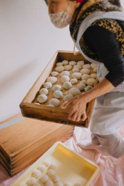 Person Carries A Wooden Box Full Of Dough Balls Photo